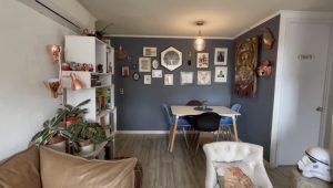 Se ve un comedor con una pared azul llena de cuadros de diferentes tamaños y colores.